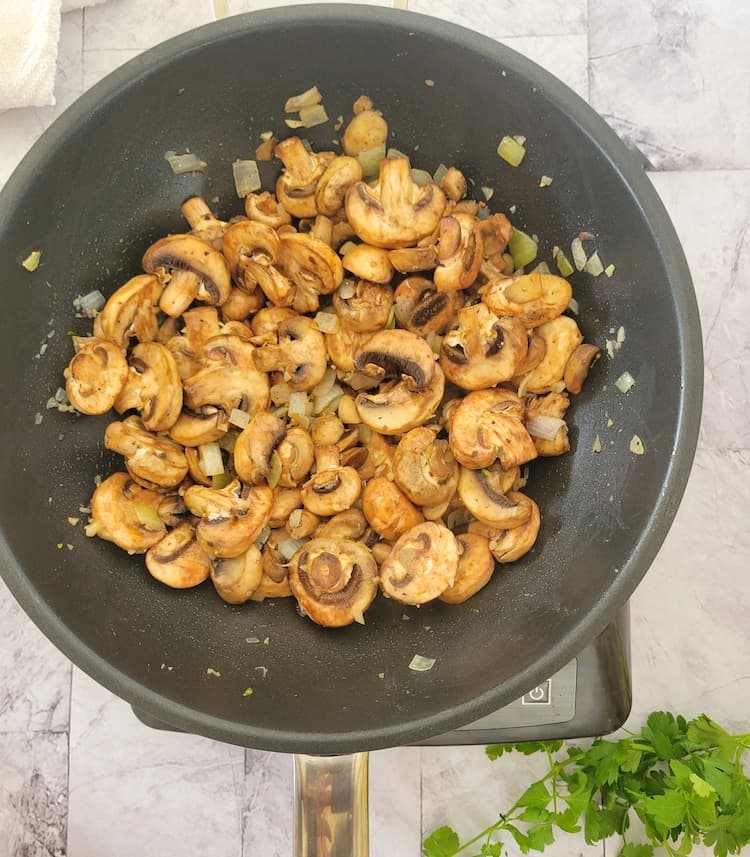 wok with cooked sliced mushrooms, diced white onion and minced garlic