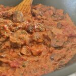 mushroom ragu in a skillet with a wooden spatula