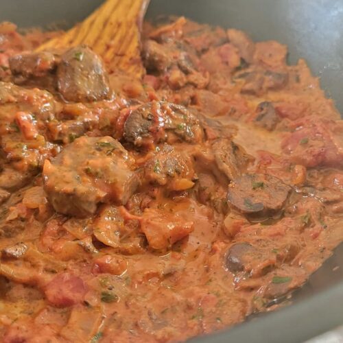 mushroom ragu in a skillet with a wooden spatula