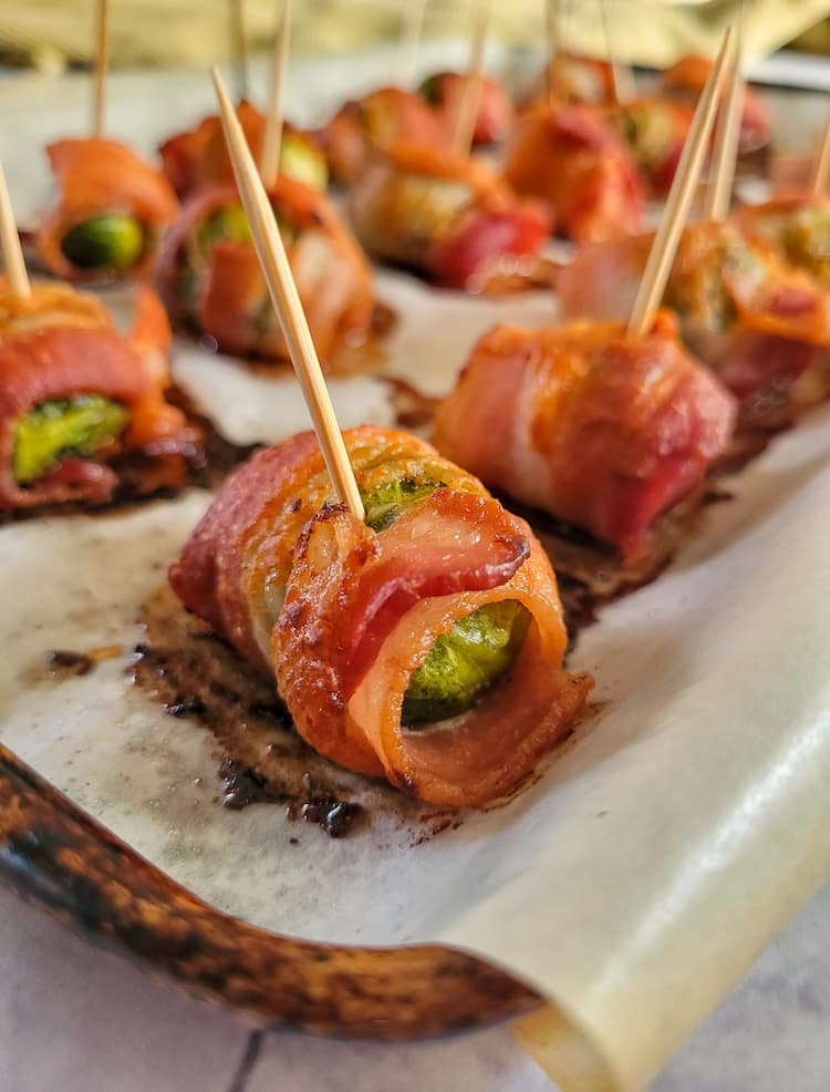bacon wrapped brussels sprouts with toothpicks in them on a parchment lined baking sheet
