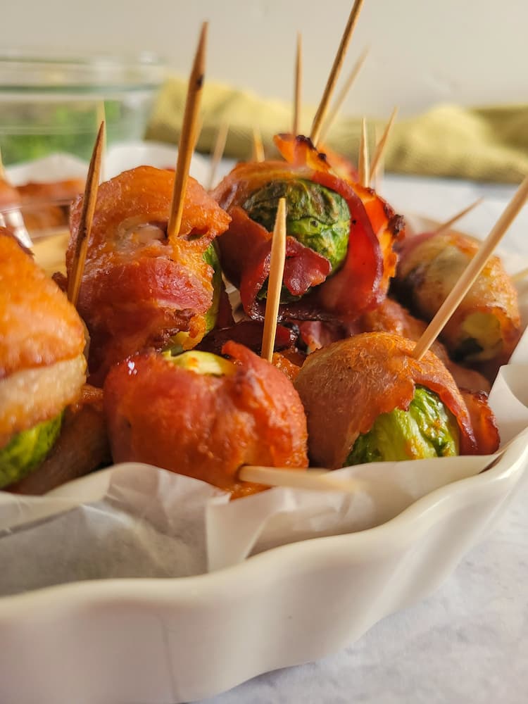 side view of a tray of bacon wrapped brussels sprouts with toothpicks in them