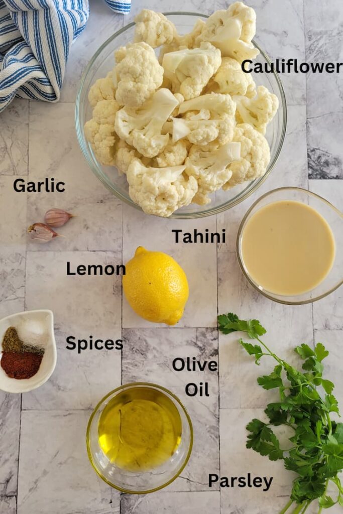ingredients for cauliflower hummus - cauliflower, tahini, lemon, olive oil, parsley, spices, garlic