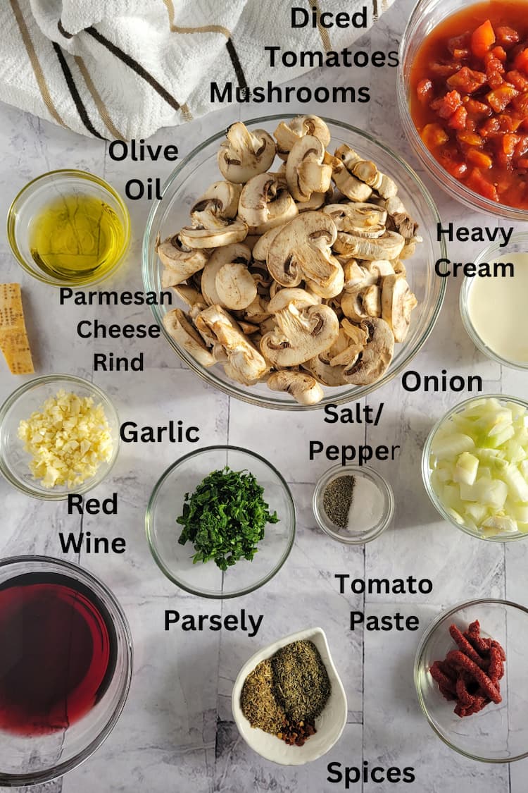 ingredients for recipe for mushroom ragu - mushrooms, diced tomatoes, heavy cream, onion, parmesan cheese rind, olive oil, salt/pepper, parsley, garlic, spices, red wine, tomato paste