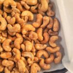 close up of a parchment lined baking sheet full of candied cashews.