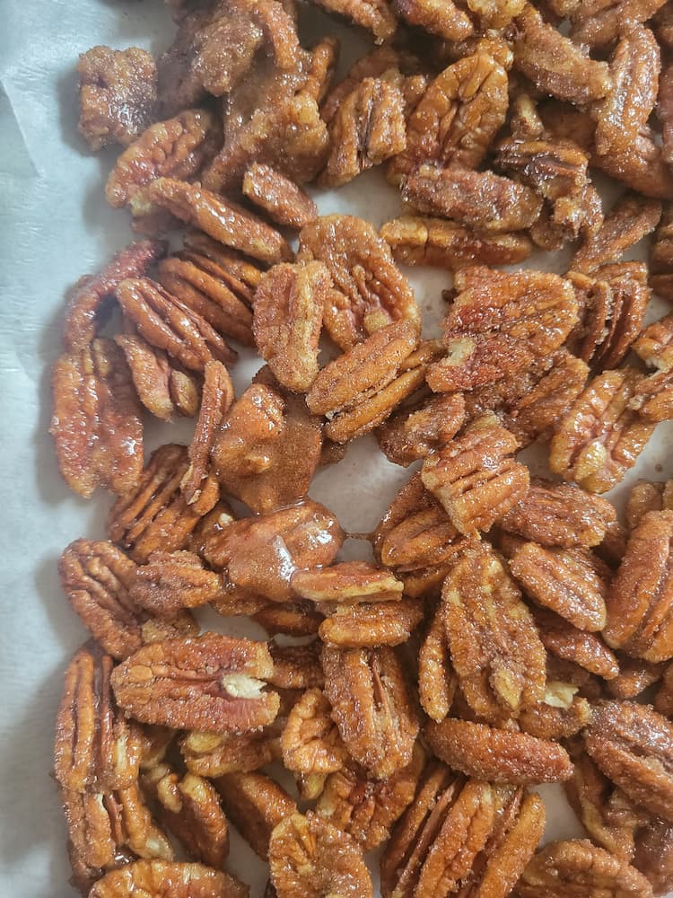 close up of spiced candied pecans on a parchment lined baking sheet