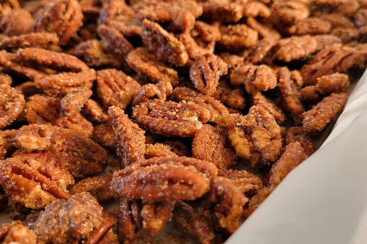 side view of spiced candied pecans on a parchment lined baking sheet