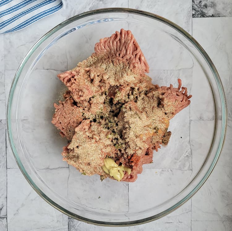 bowl of raw ground beef with spices and dijon mustard