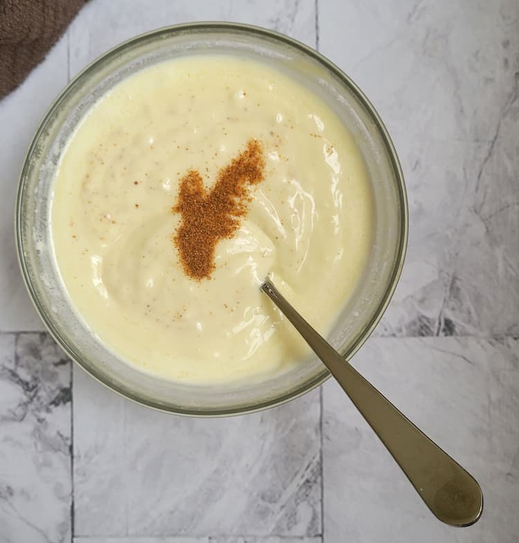 bowl of aioli with cayenne pepper on top, spoon in the bowl