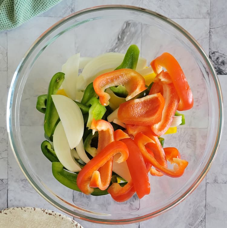 bowl of sliced raw tri-coloured peppers and white onion