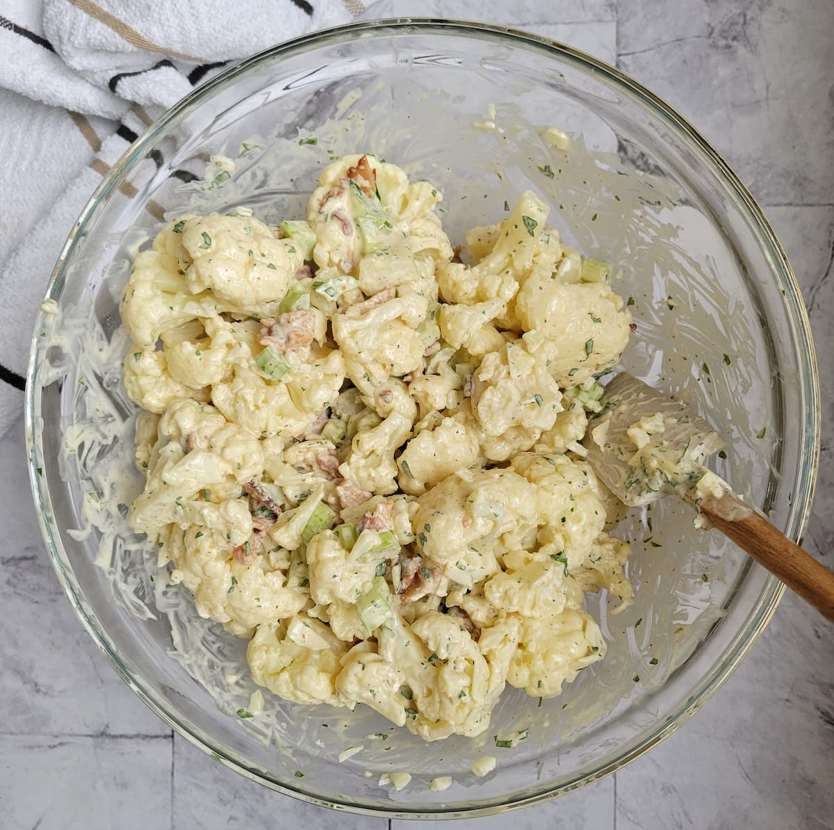 bowl of cauliflower florets mixed with a creamy sauce and chopped celery and bacon