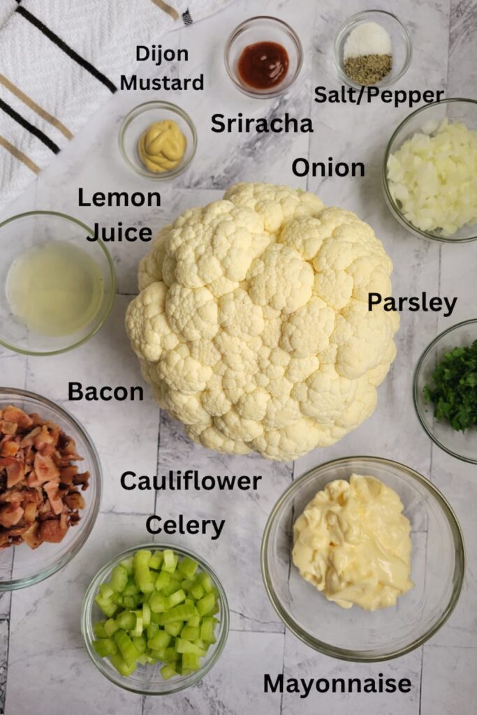 ingredients for cauliflower 'potato' salad - cauliflower, mayonnaise, bacon, celery, parsley, onion, sriracha, dijon mustard, salt/pepper, lemon juice