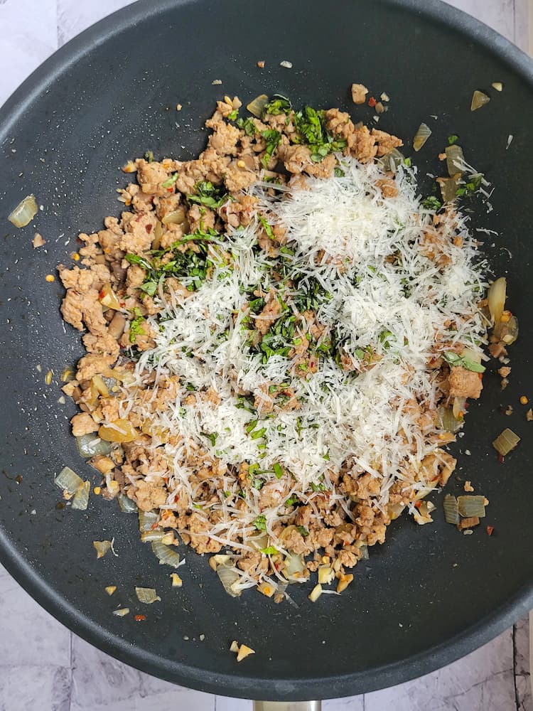 wok with browned italian sausage, freshly grated parmesan cheese and chopped basil
