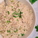 bowl of mashed turnips garnished with fresh chopped parsley, more parsley in the background