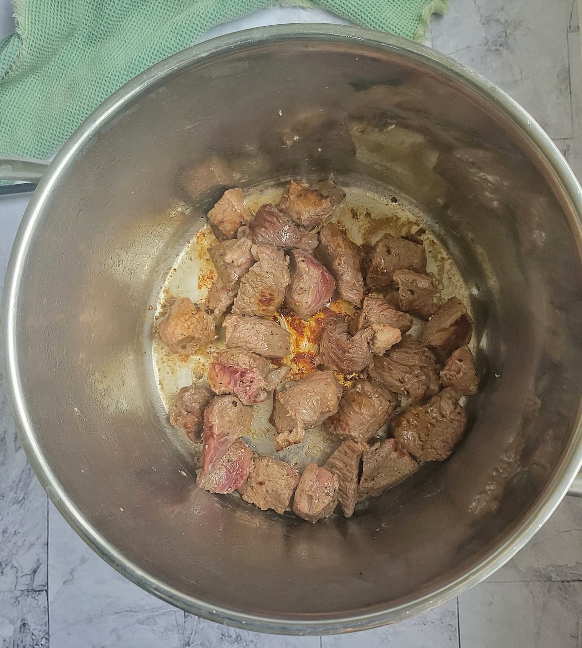 semi cooked beef cubes in the bottom of a pot