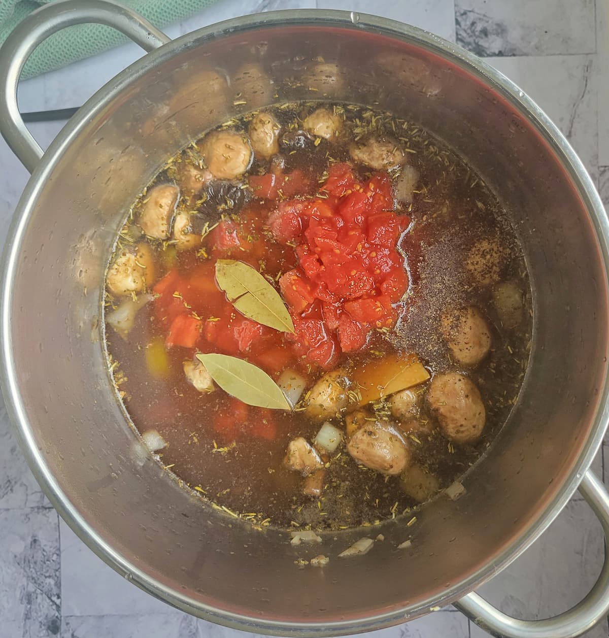 pot with broth, mushrooms, diced tomatoes and 2 bay leaves