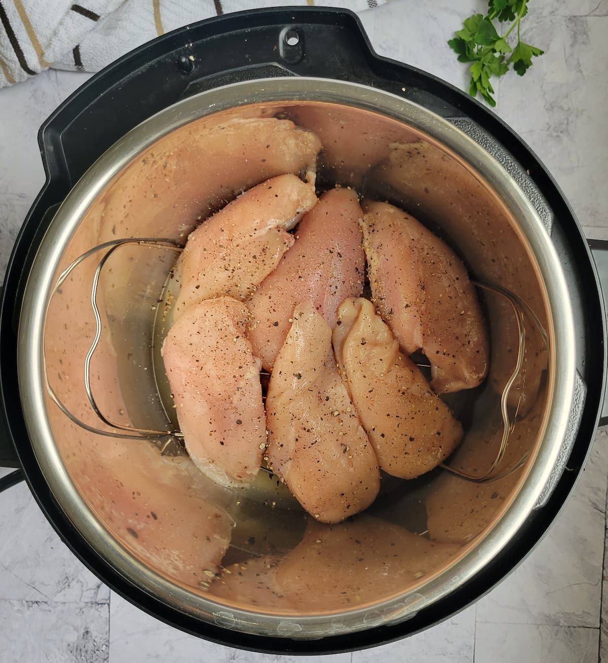 6 raw chicken breasts seasoned with salt and pepper on a metal trivet in an instant pot