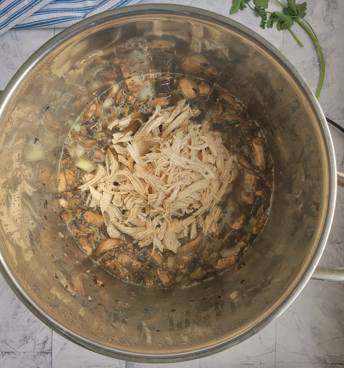 shredded chicken in a large pot with broth, sliced mushrooms, onions and spices
