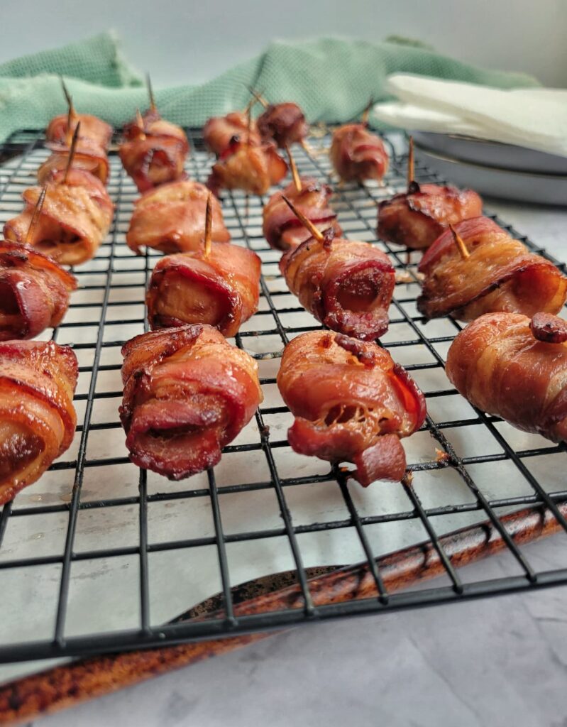 bacon wrapped water chestnuts with toothpicks on a parchment lined baking sheet