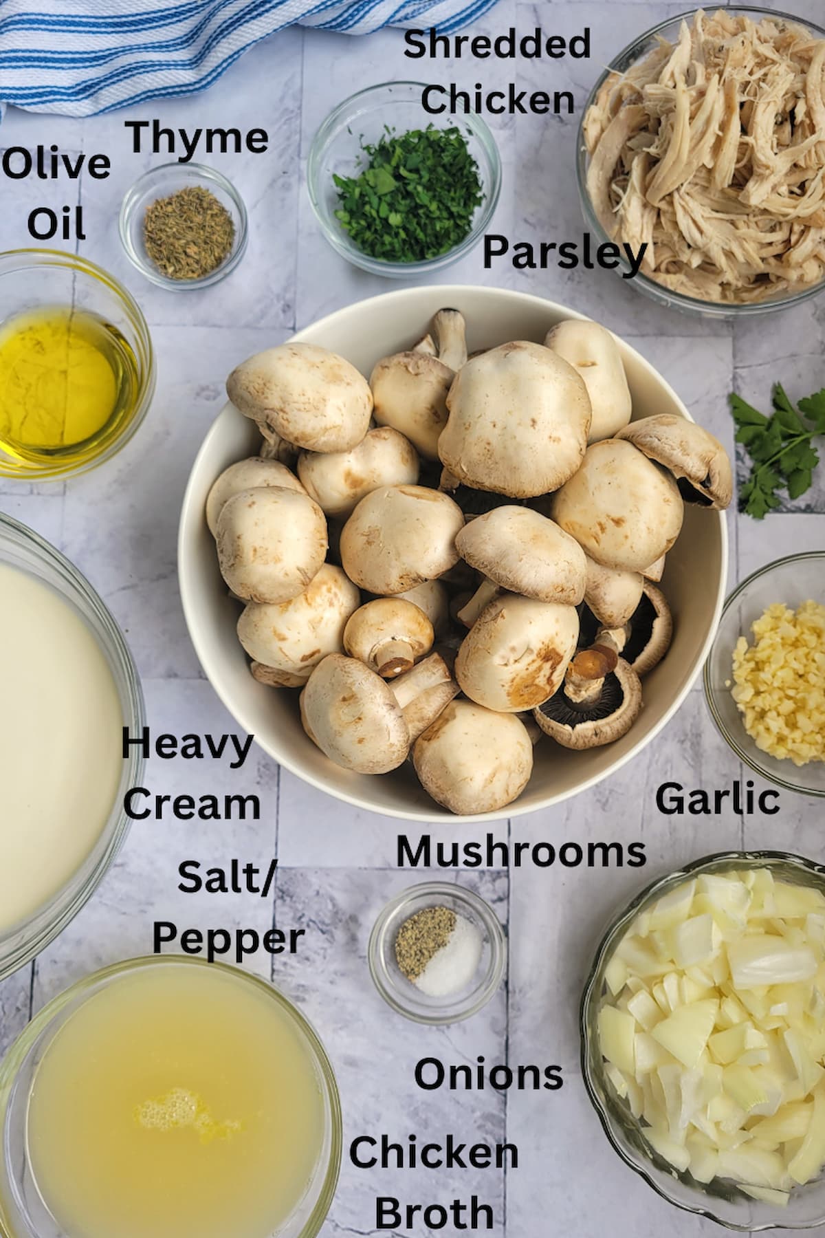 ingredients for cream of mushroom chicken soup - mushrooms, shredded chicken, parsley, thyme, olive oil, garlic, heavy cream, chicken broth, salt/pepper, onions