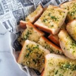 basket of fresh sliced garlic bread with fresh minced garlic and chopped parsley