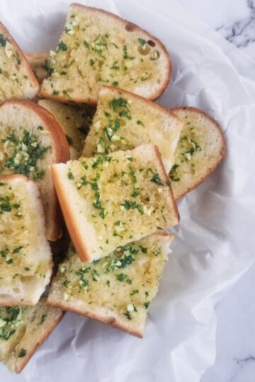 basket of fresh sliced garlic bread with fresh minced garlic and chopped parsley