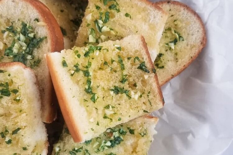 basket of fresh sliced garlic bread with fresh minced garlic and chopped parsley