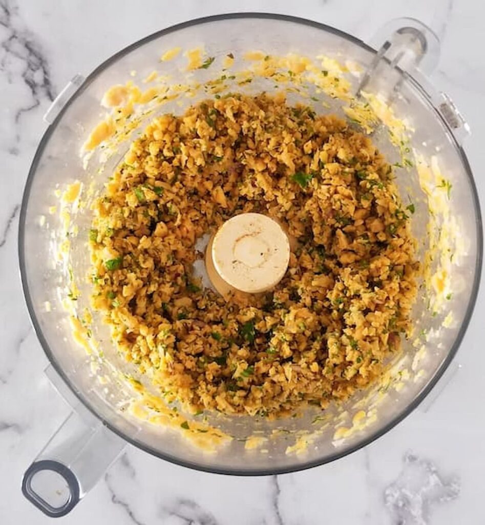 a food processor bowl showcasing finely processed chickpea patty mixture