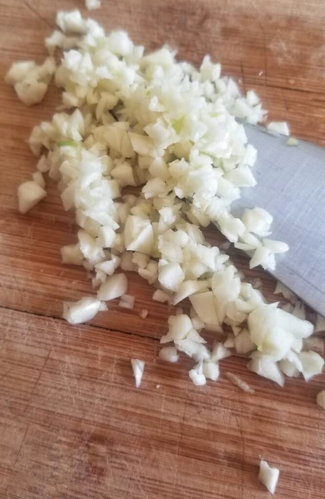 chopped garlic with a knife on a cutting board