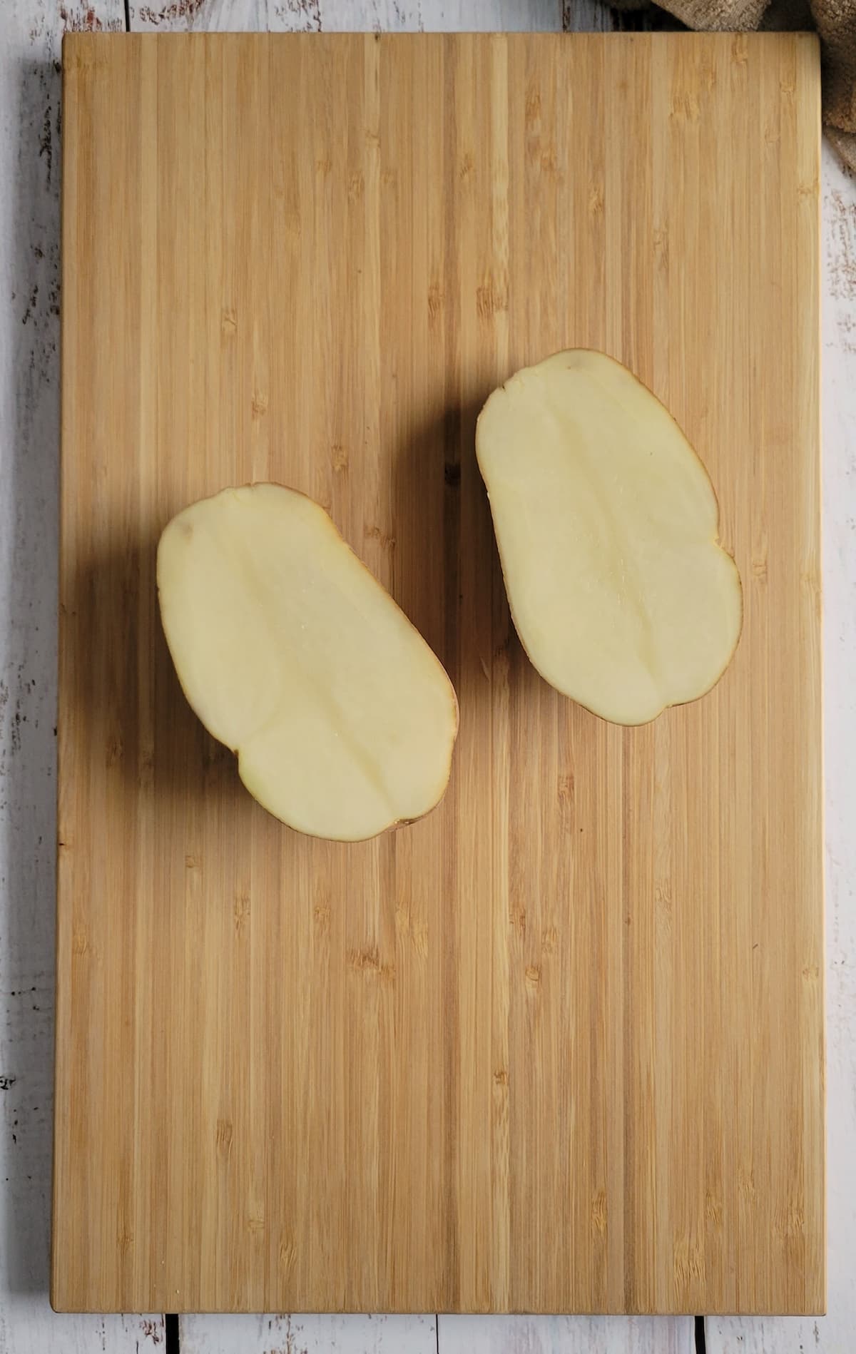 two potato halves face up on a cutting board