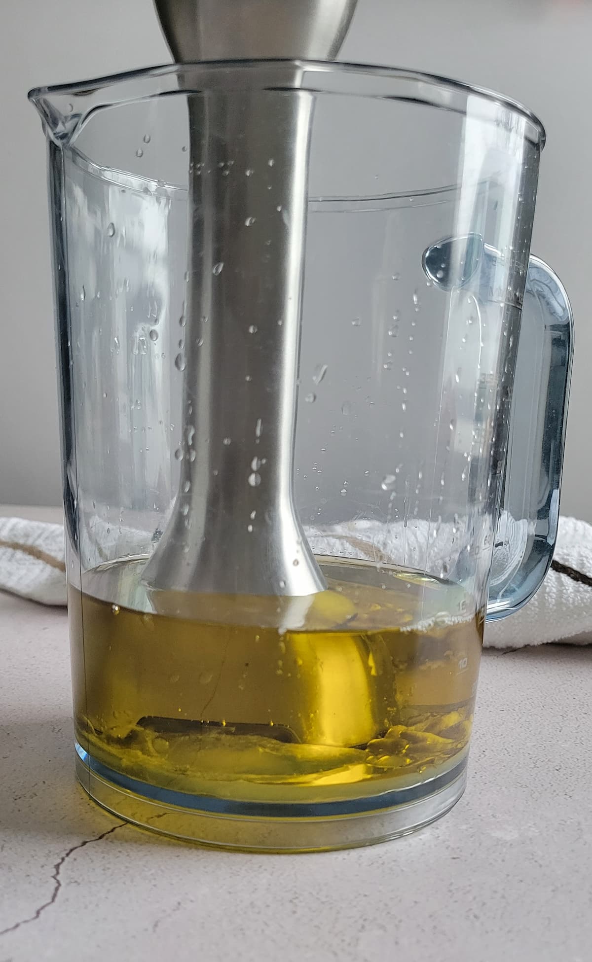 stick of an immersion blender in a jug with oil