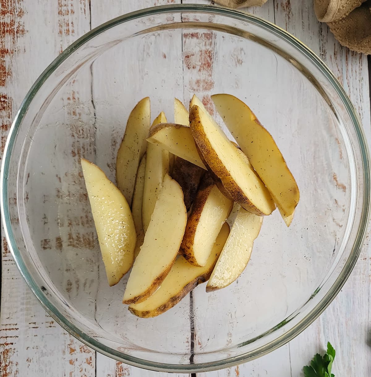 raw potato wedges in a bowl with seasonings