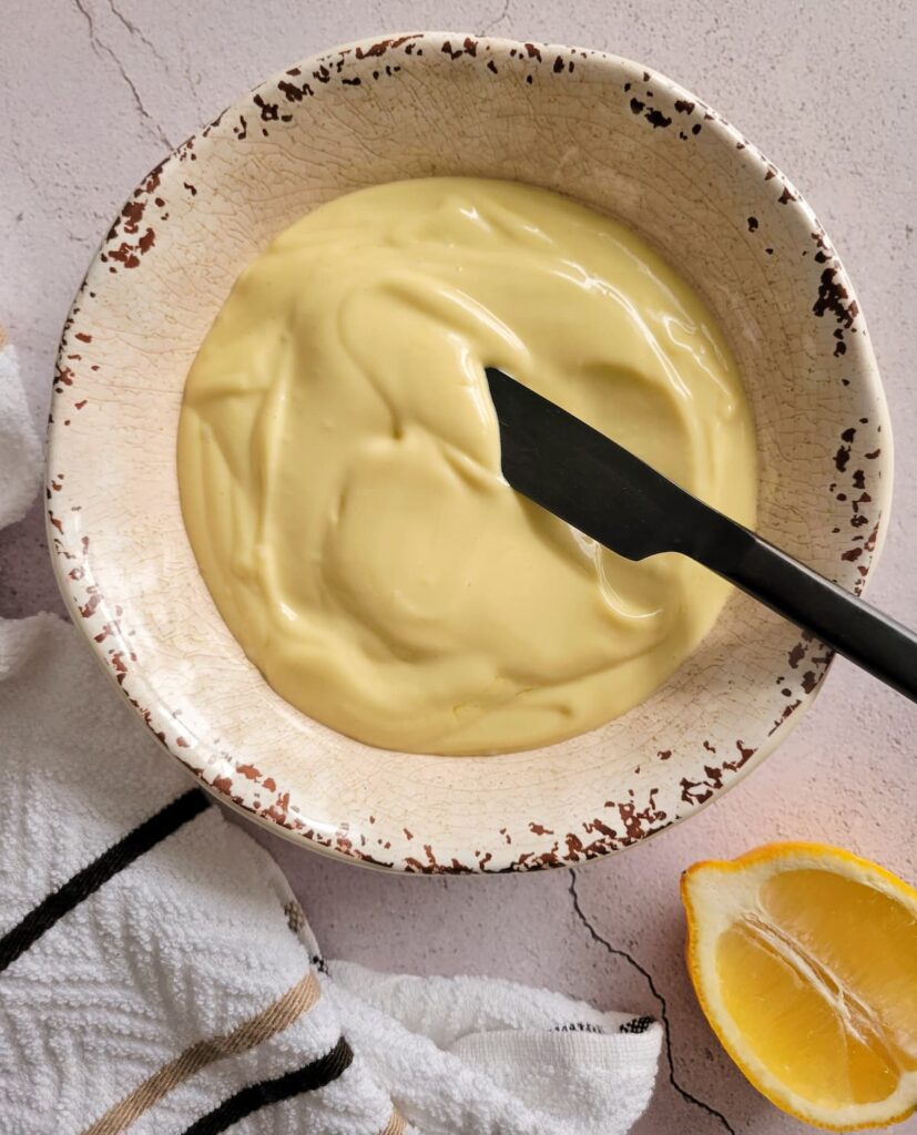 mayo in a bowl with a black knife, half a lemon underneath it