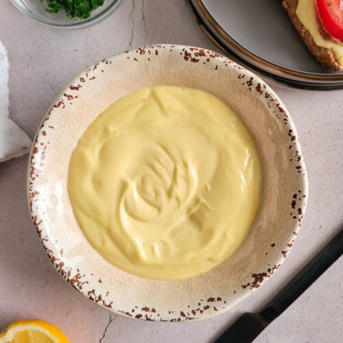 bowl of mayo, black knife beside it, bowl of chopped parsley, half a lemon and tomato mayo toasts in the background