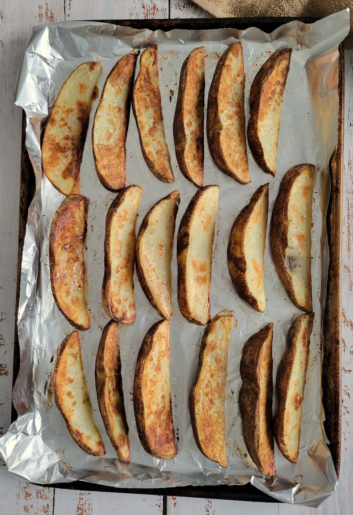 crispy baked potato wedges in a single layer on an aluminum lined baking sheet