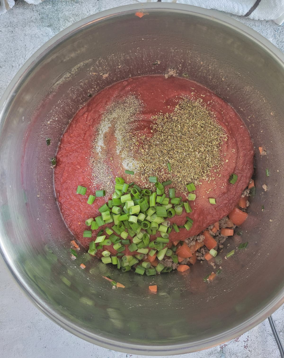 pot of tomato sauce with seasonings and green onions on top