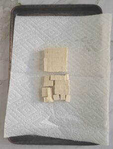 cubed tofu on paper towel on a baking sheet