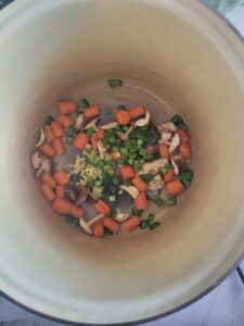 pot with carrots, ginger, green onions and mushrooms