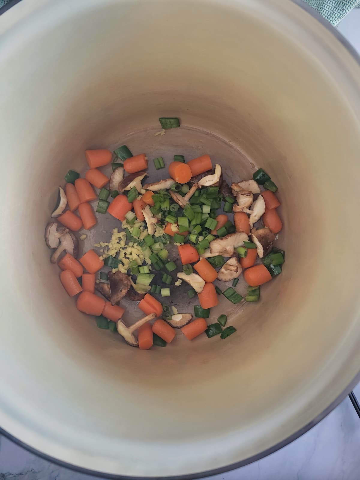 pot with carrots, ginger, green onions and mushrooms