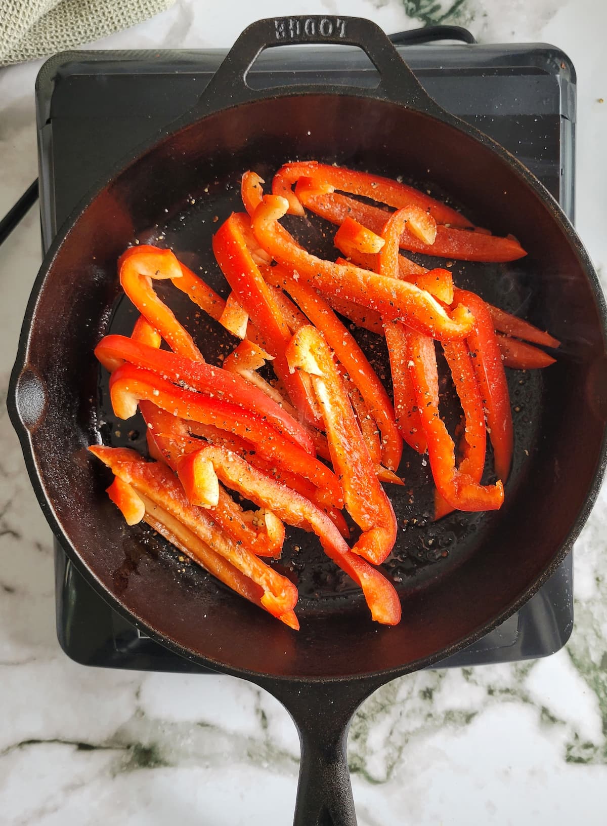 sliced red bell peppers seasoned with salt and pepper in a black cast iron skillet