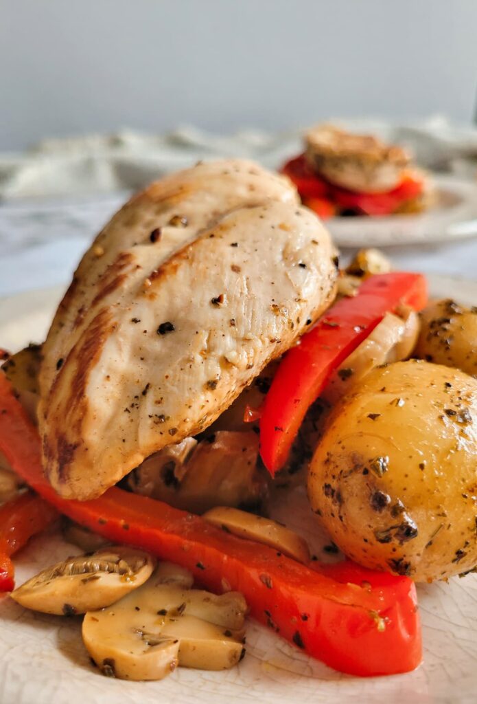 seasoned cooked chicken breast over sliced red bell peppers, mushrooms and potatoes