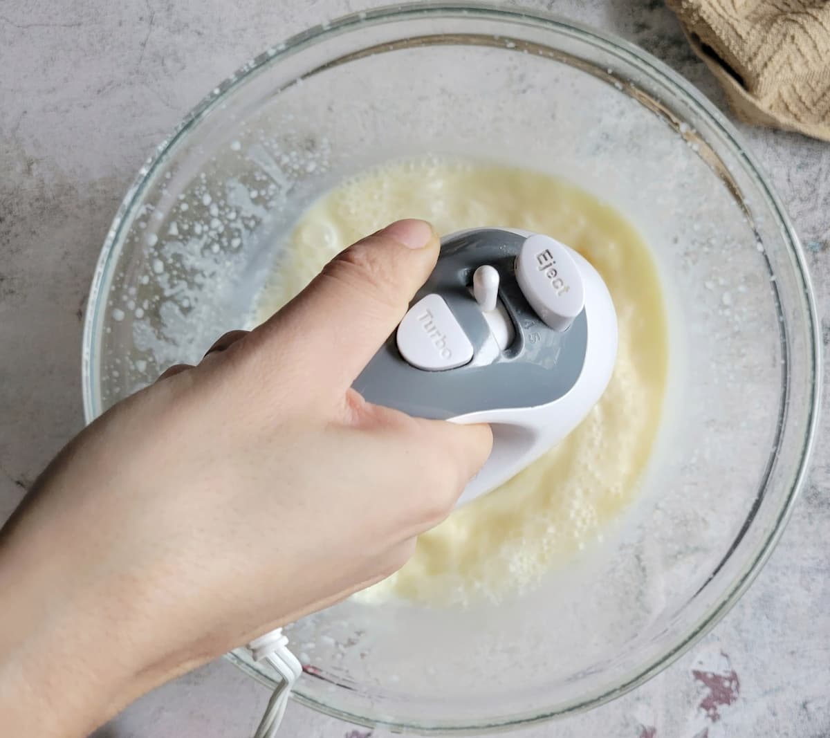hand with an electric mixer blending vanilla pudding in a bowl