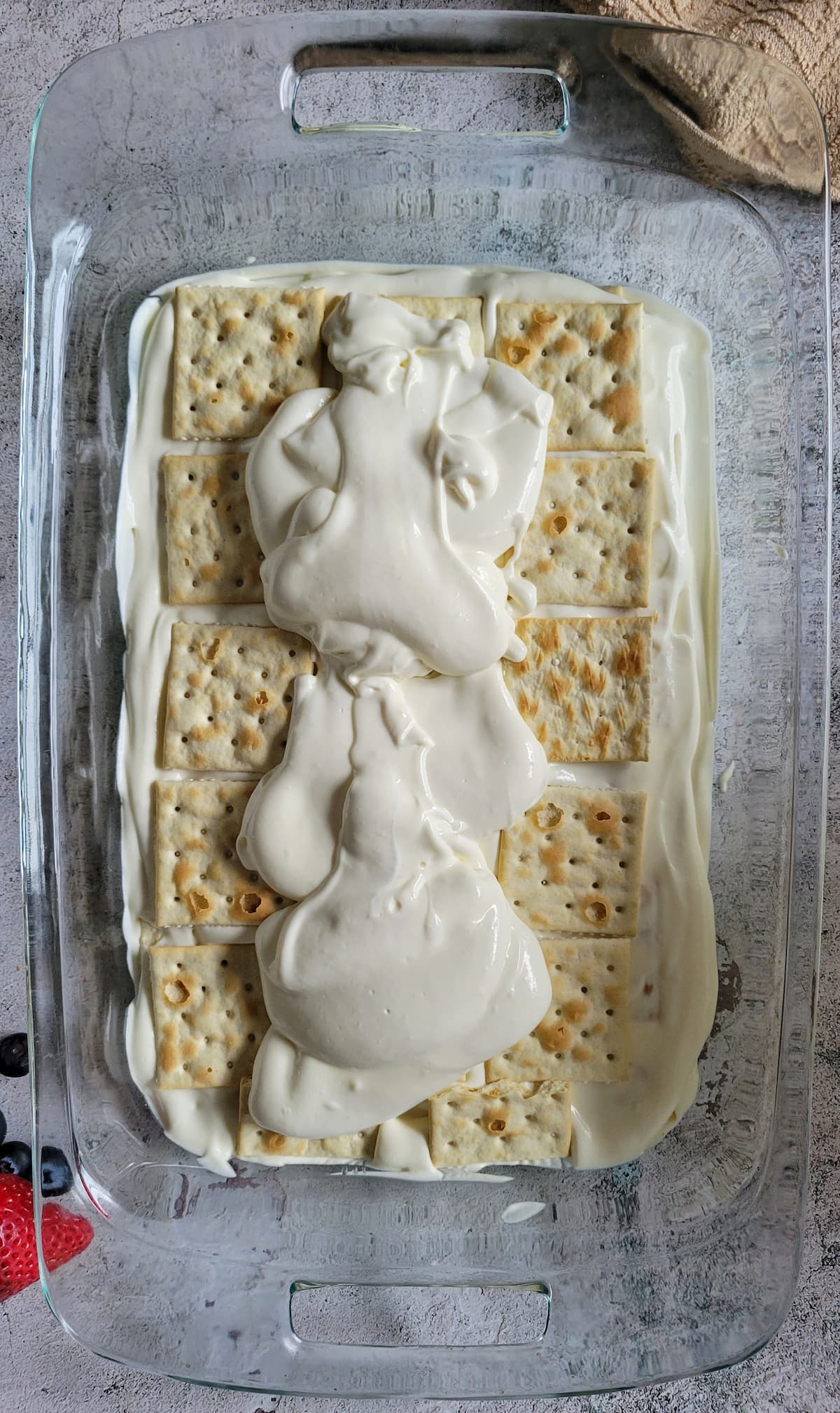 glass baking dish layered with whipped cream and saltine crackers