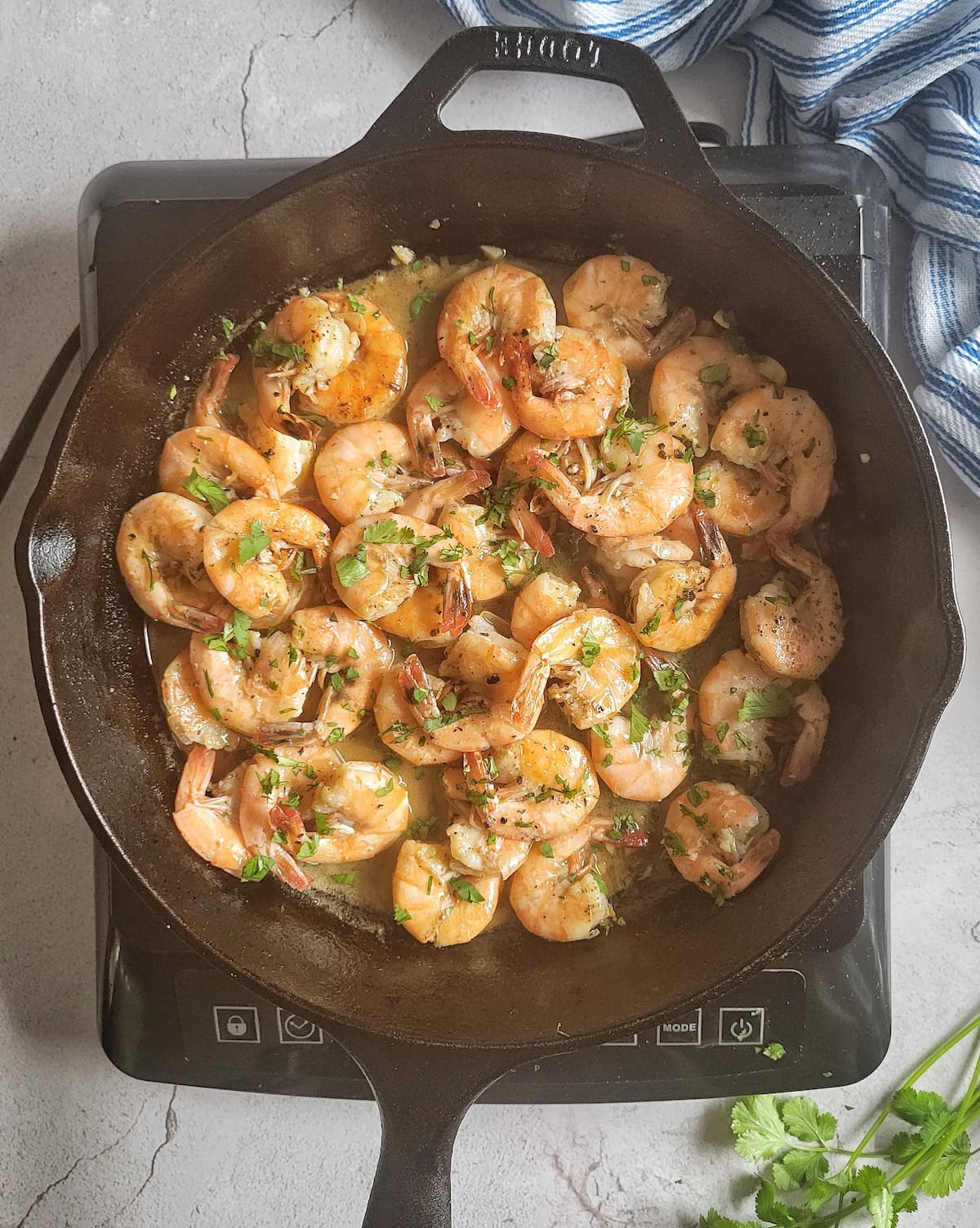 sauteed shrimp in a cast iron skillet garnished with fresh chopped parsley
