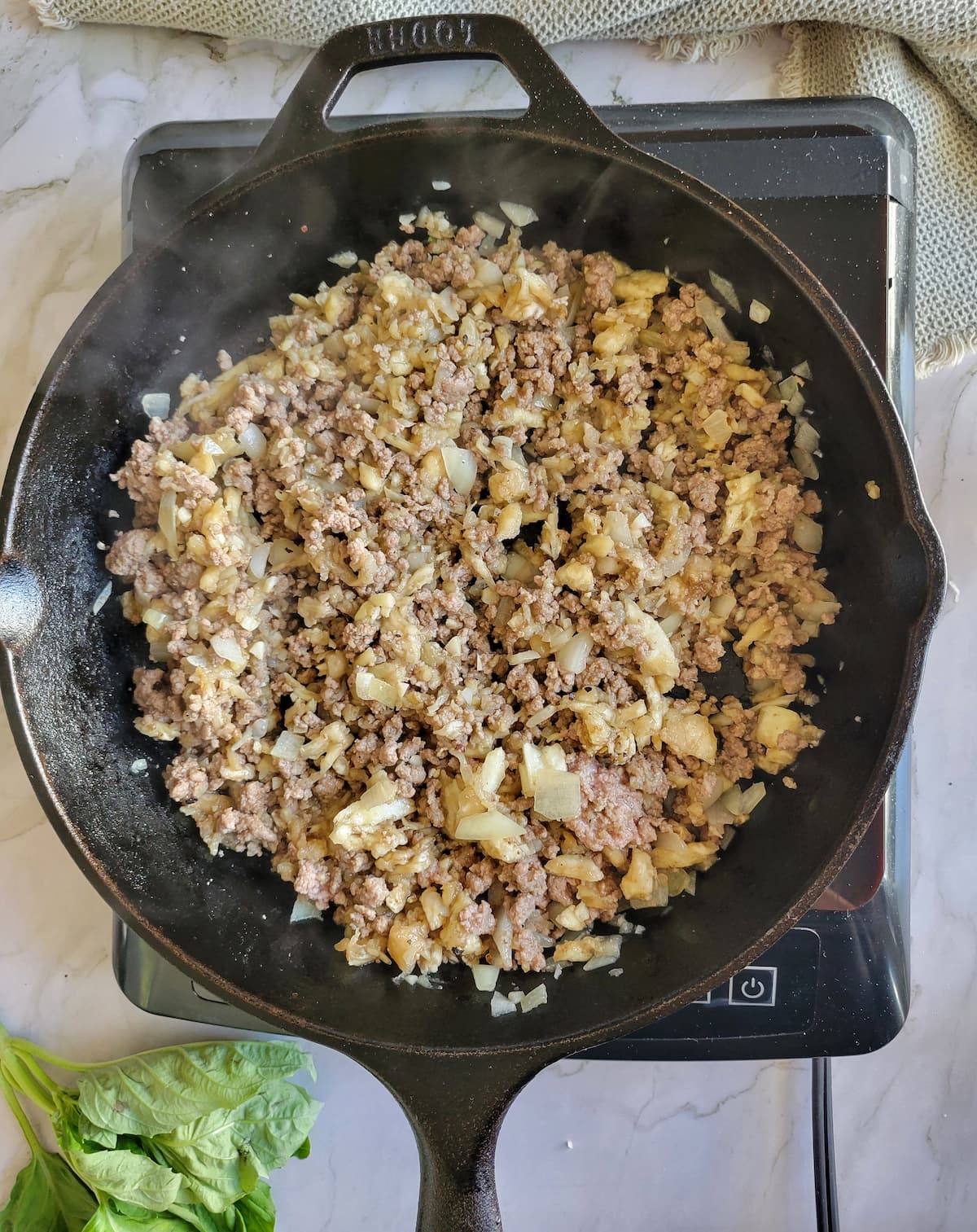 browned ground beef and minced eggplant and onion in a cast iron skillet
