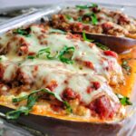 lasagna stuffed eggplant in a baking dish topped with fresh chopped basil