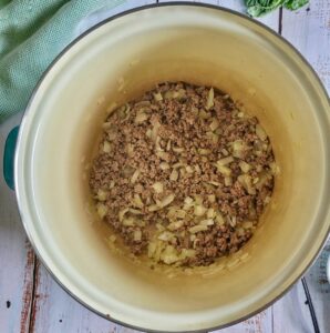 cooked ground beef and diced white onions in a pot