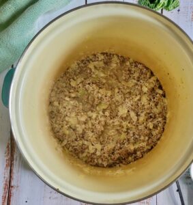 cooked ground beef, diced white onions, broth and rice in a pot
