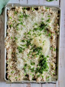 sheet pan of cooked rice, peas and ground beef with freshly chopped parsley and grated parmesan cheese on top