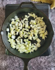 diced white onion in a cast iron skillet on a burner