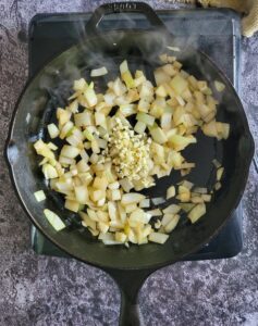 diced onions and minced garlic in a cast iron skillet on a burner